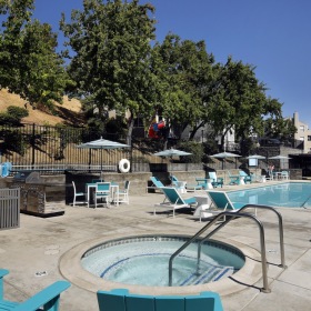 a hot tub and chairs by a pool