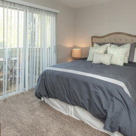 a bedroom with a bed and lamps and balcony access